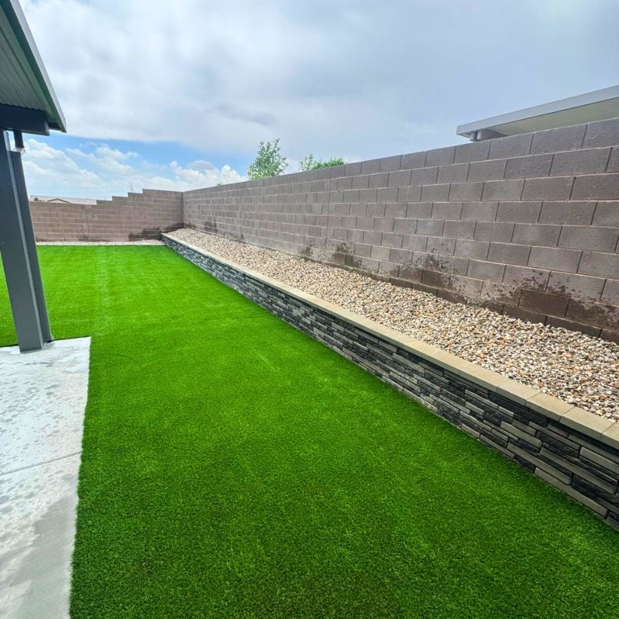 Artificial turf lawn beside stacked stone retaining wall